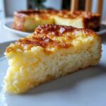 A close-up slice of moist cassava cake with a beautifully caramelized, golden-brown top, served on a white plate.