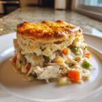A single serving of creamy slow cooker chicken pot pie topped with a golden, flaky biscuit.