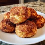 A close-up stack of freshly baked, soft snickerdoodle cookies generously coated in cinnamon sugar.