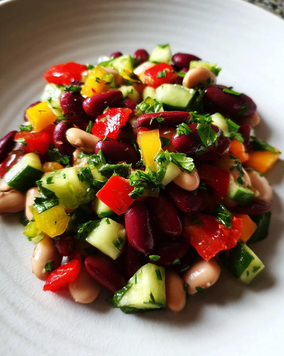 Close-up of a colorful Mediterranean bean salad featuring kidney beans, cannellini beans, chopped cucumber, bell peppers, and parsley.