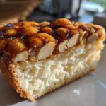A close-up cross-section of a slice of bee sting cake showing the fluffy interior and sticky almond topping.