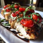 Close-up of sliced caprese chicken topped with roasted cherry tomatoes, fresh basil, and balsamic glaze.