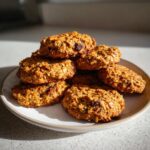 A stack of chewy breakfast cookies made with oats and visible chocolate chips, brightly lit.