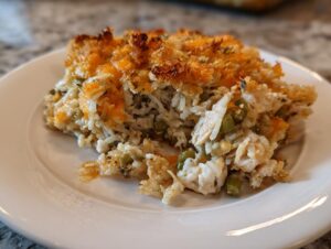 A close-up serving of creamy chicken wild rice casserole topped with melted, browned cheese and breadcrumbs.
