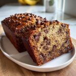 A moist chocolate chip banana bread recipe loaf, sliced to show the rich texture and abundant chocolate chips inside.