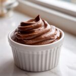 A single serving of rich, piped cottage cheese chocolate mousse in a white fluted ramekin.