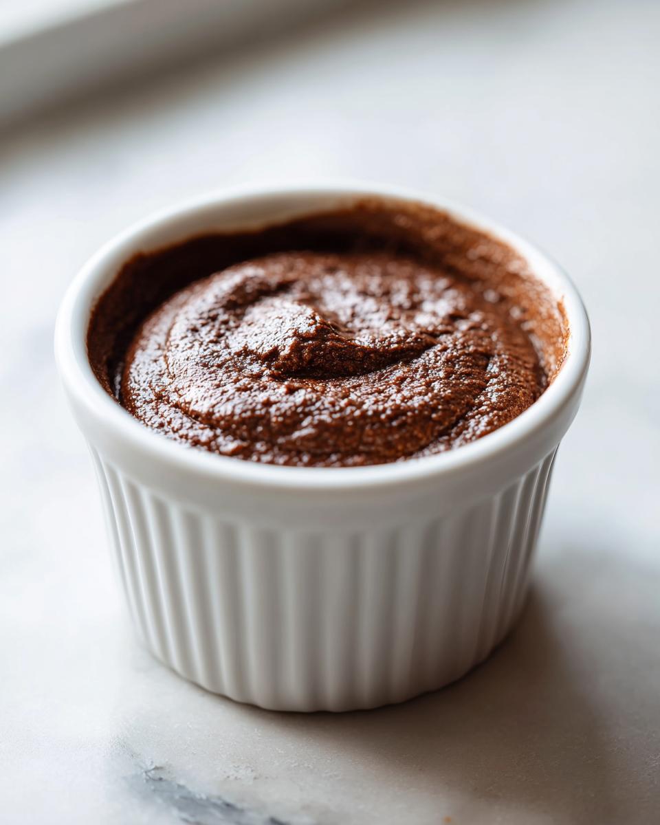 Close-up of rich, dark cottage cheese chocolate mousse served in a white fluted ramekin.