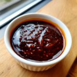 Close-up of thick, glossy homemade teriyaki sauce with visible minced garlic or ginger pieces.