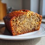 Close-up of a moist slice of homemade banana bread showing its dense, speckled crumb and caramelized crust.