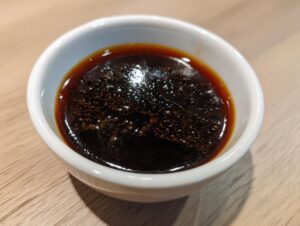 Close-up of thick, bubbling homemade teriyaki sauce in a small white dipping bowl.