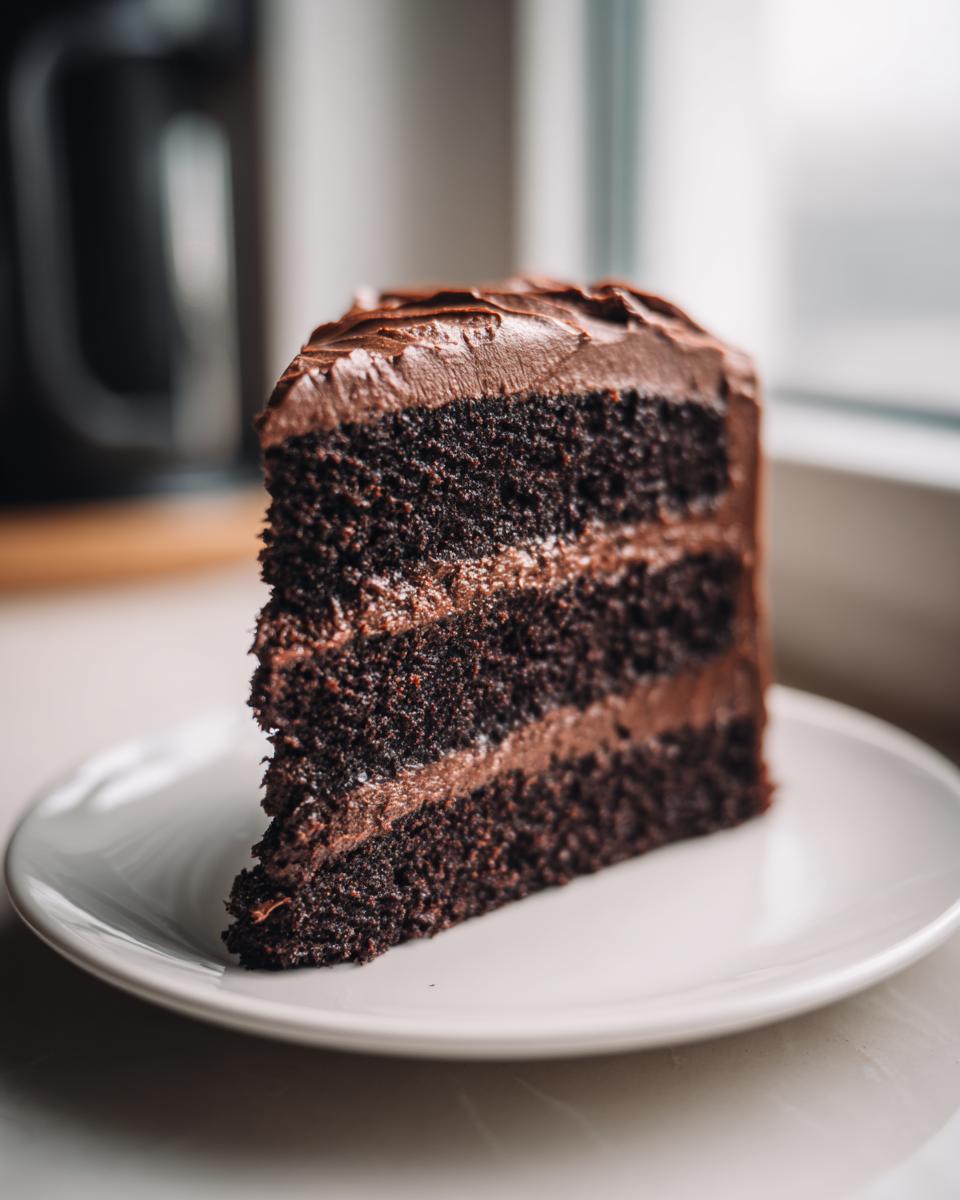 A tall, moist slice of three-layer chocolate cake recipe with thick chocolate frosting.