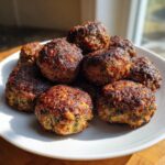 A pile of golden-brown, crispy stuffing balls recipe served on a white plate, catching the sunlight.