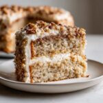 A close-up slice of white German chocolate cake with coconut pecan frosting layers.