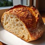 Close-up of a freshly baked loaf of 4-ingredient bread, showing the open crumb structure and dark, crusty top.