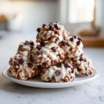 A stack of homemade avalanche cookies drizzled with white chocolate and topped with mini chocolate chips.