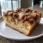 A close-up of a thick, moist slice of french toast casserole topped with gooey cinnamon streusel.