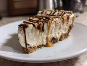 A decadent slice of no bake peanut butter pie on a white plate, topped with chocolate and peanut butter drizzles.